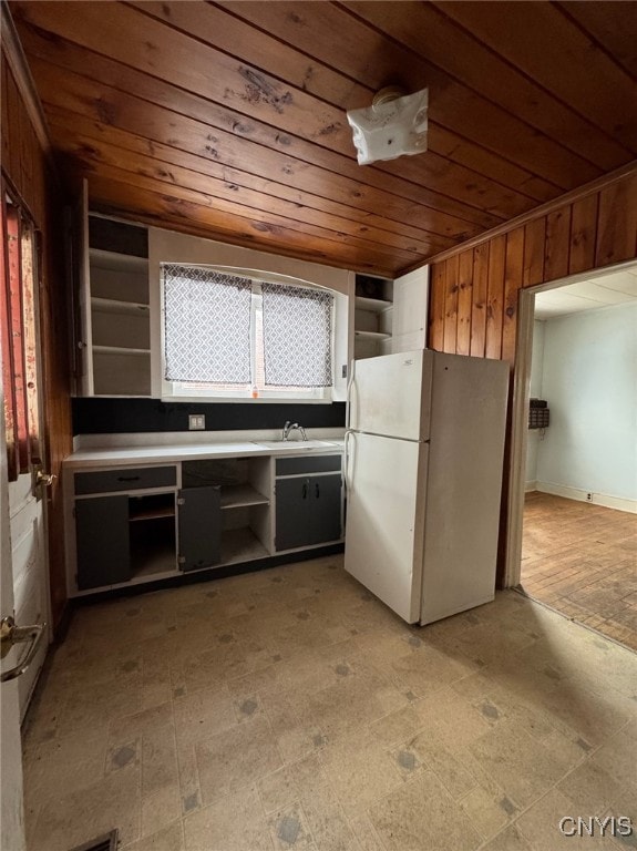 kitchen with sink, white fridge, wooden walls, and wood ceiling