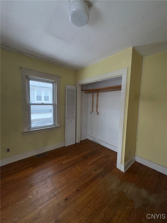 unfurnished bedroom with dark hardwood / wood-style flooring and a closet