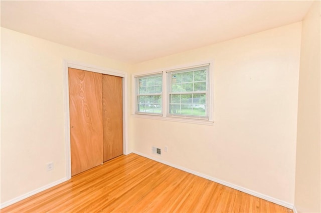 unfurnished bedroom with light hardwood / wood-style flooring and a closet