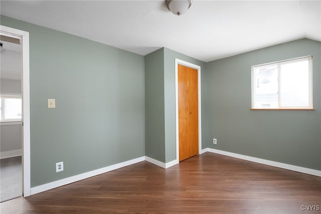 unfurnished bedroom with a closet, dark wood-type flooring, and lofted ceiling