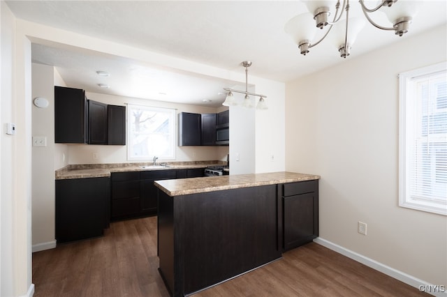 kitchen with appliances with stainless steel finishes, dark hardwood / wood-style flooring, pendant lighting, and sink