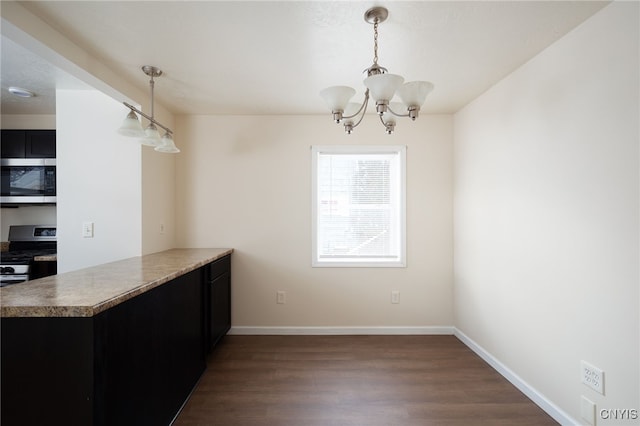 kitchen featuring dark hardwood / wood-style floors, a notable chandelier, kitchen peninsula, decorative light fixtures, and appliances with stainless steel finishes