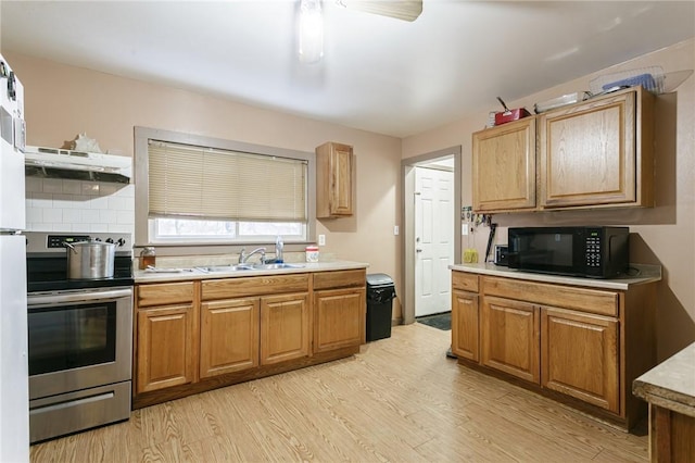 kitchen featuring sink, ceiling fan, light hardwood / wood-style floors, stainless steel range oven, and extractor fan