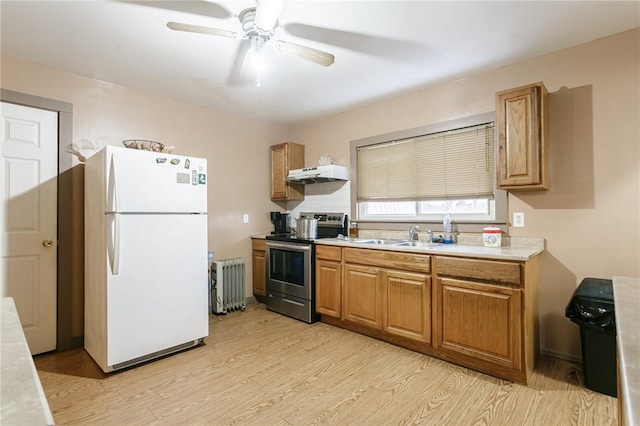 kitchen with light wood-type flooring, radiator, sink, electric stove, and white fridge