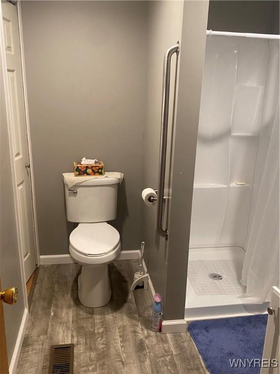 bathroom with hardwood / wood-style flooring, toilet, and walk in shower