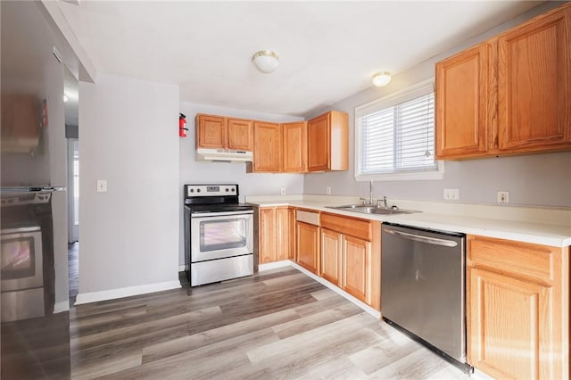 kitchen with appliances with stainless steel finishes, light wood-type flooring, and sink