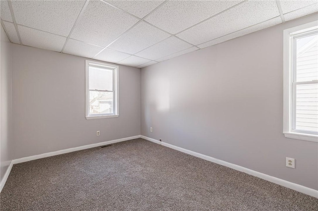 carpeted spare room featuring a drop ceiling