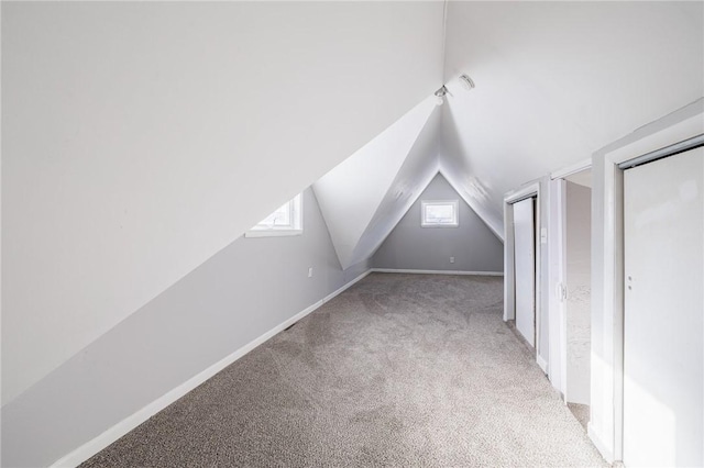 additional living space featuring light colored carpet and lofted ceiling