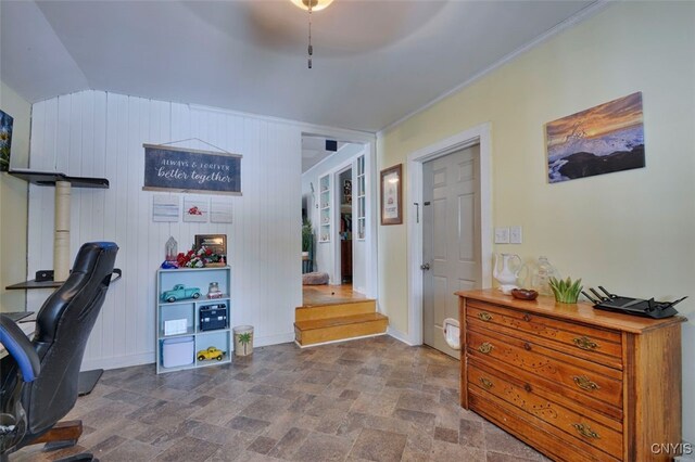 office area with vaulted ceiling, ceiling fan, ornamental molding, and wood walls