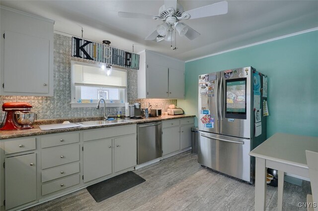 kitchen featuring sink, decorative backsplash, ceiling fan, light hardwood / wood-style floors, and stainless steel appliances