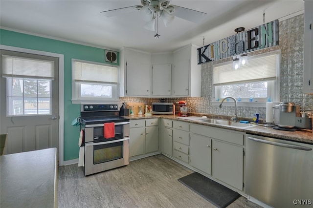 kitchen featuring sink, stainless steel appliances, tasteful backsplash, white cabinets, and light wood-type flooring