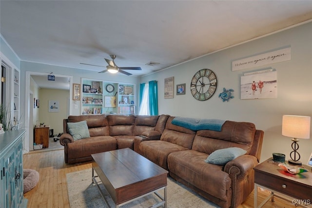 living room featuring ceiling fan, crown molding, light hardwood / wood-style floors, and built in shelves