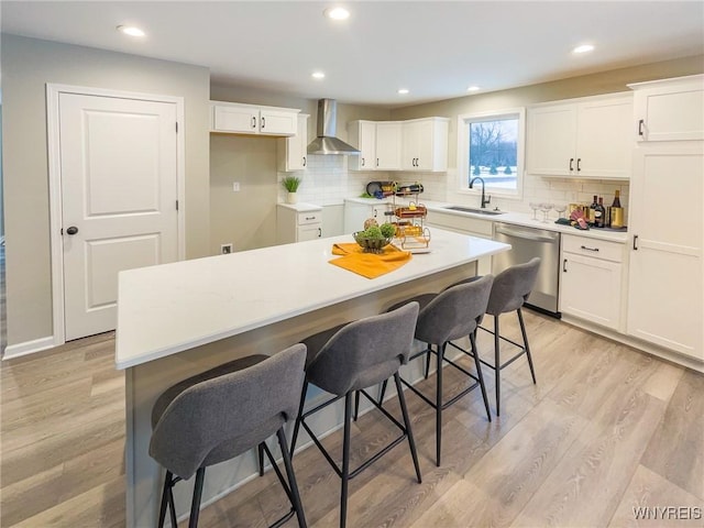 kitchen featuring stainless steel dishwasher, a center island, white cabinets, and a breakfast bar area