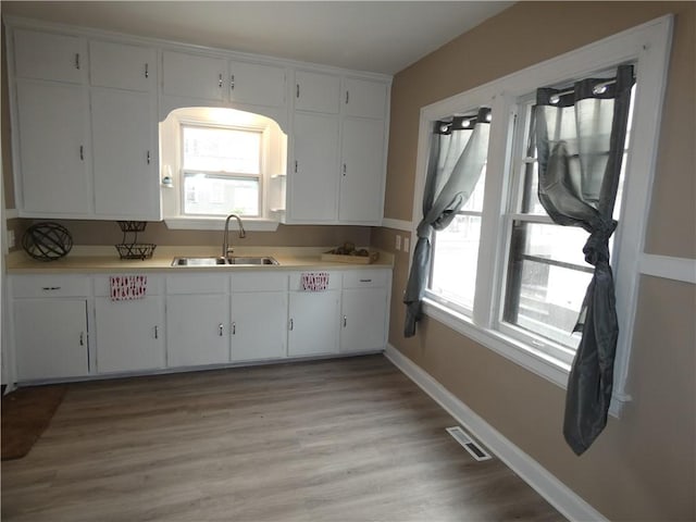 kitchen featuring white cabinets, light hardwood / wood-style floors, and sink