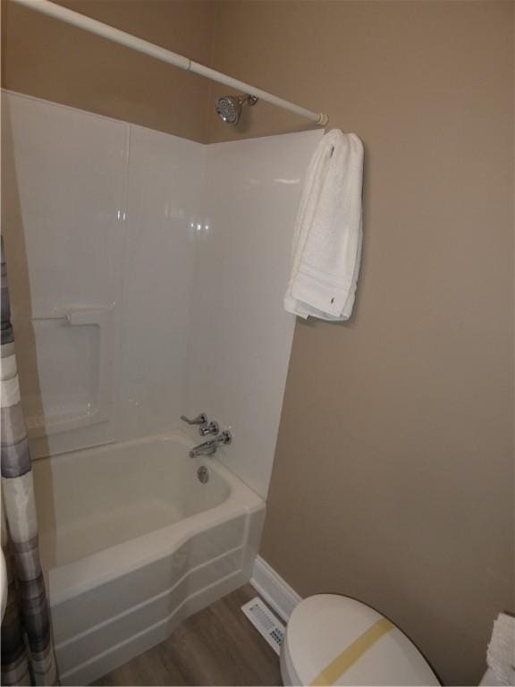 bathroom with hardwood / wood-style floors, toilet, and shower / tub combo with curtain