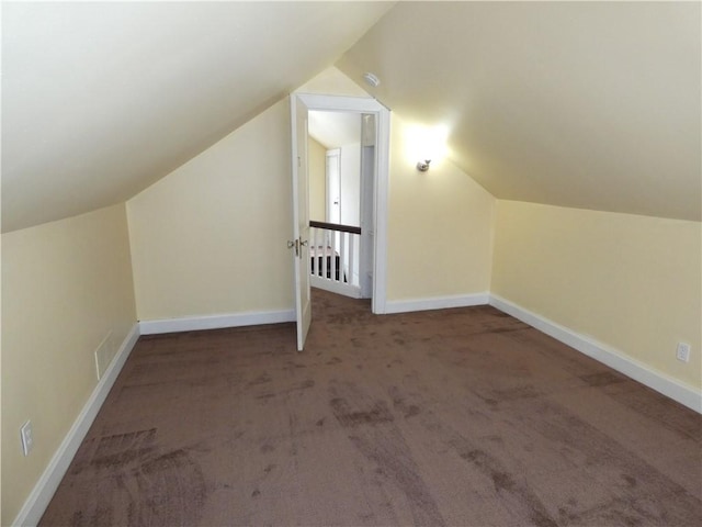 bonus room with dark colored carpet and lofted ceiling