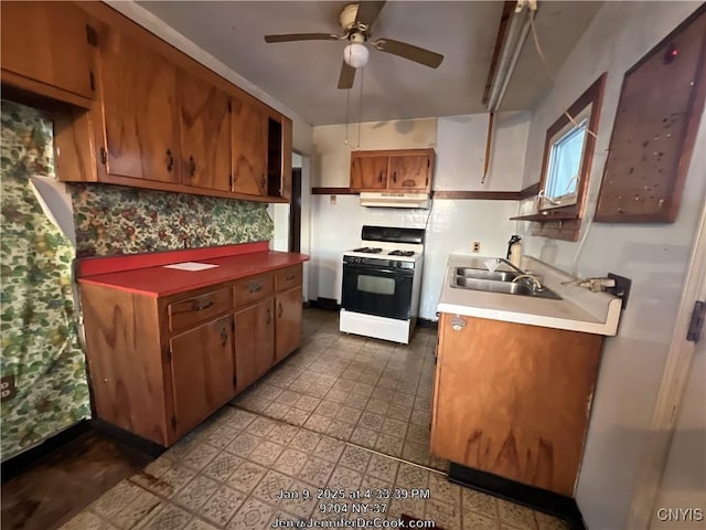 kitchen featuring white gas range, ceiling fan, sink, and decorative backsplash