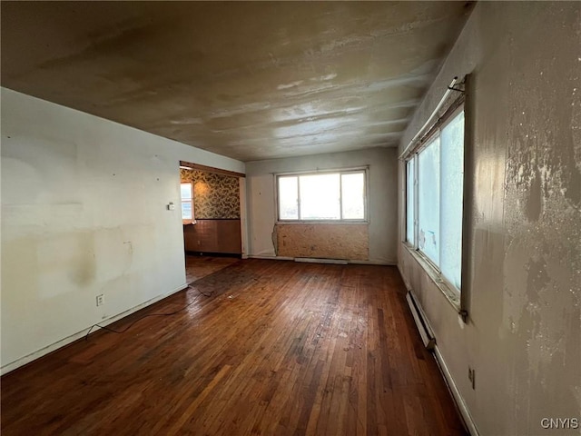 empty room with dark hardwood / wood-style flooring and a baseboard radiator