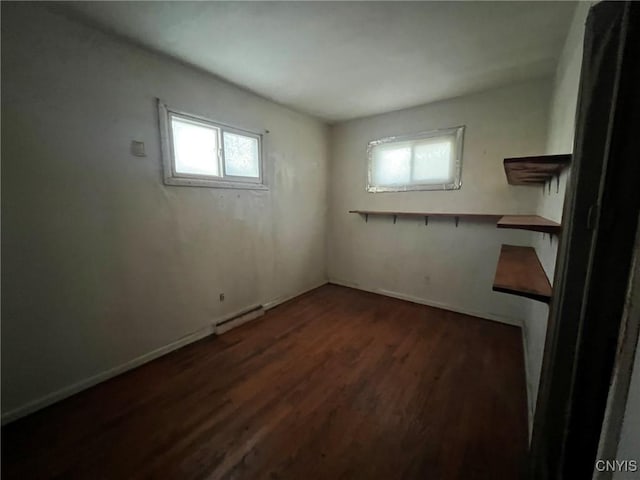 basement with dark hardwood / wood-style flooring, a baseboard radiator, and plenty of natural light