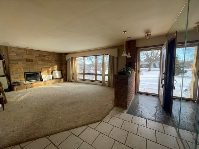 unfurnished living room featuring carpet flooring, a stone fireplace, and a baseboard radiator