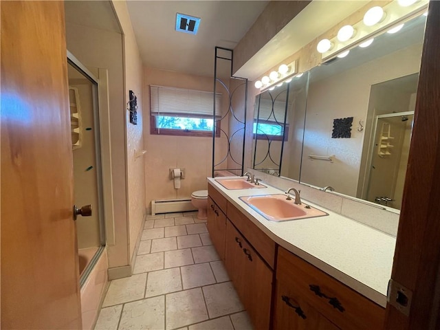 full bathroom with vanity, a baseboard heating unit, tile patterned floors, combined bath / shower with glass door, and toilet