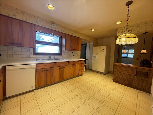 kitchen with decorative light fixtures, decorative backsplash, white appliances, and sink