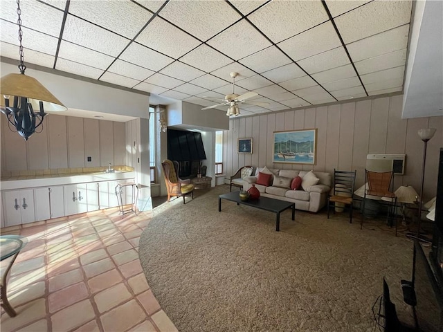 tiled living room with a wall mounted AC, ceiling fan, a drop ceiling, and sink