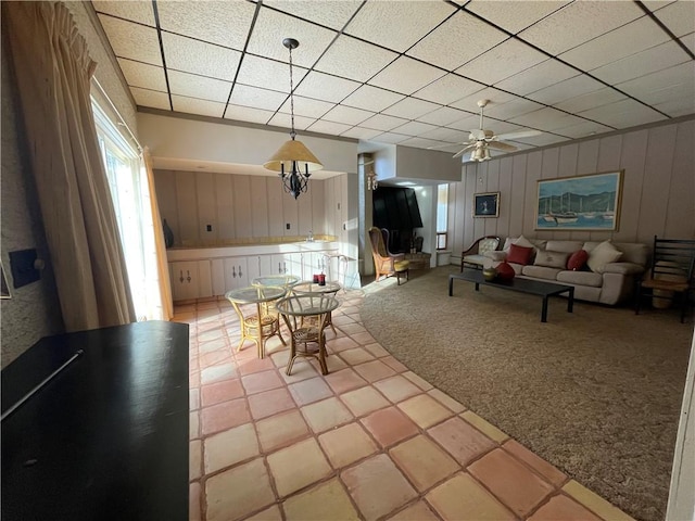 unfurnished living room with ceiling fan, a drop ceiling, and light carpet