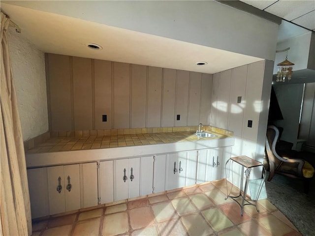 kitchen with tile countertops, white cabinets, and sink