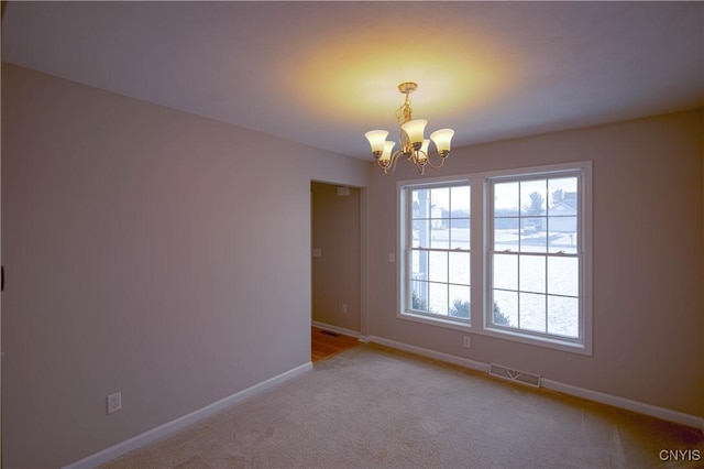 carpeted empty room featuring a chandelier