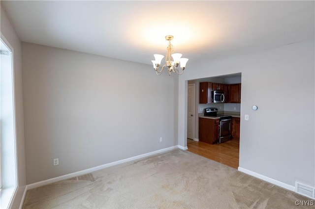 unfurnished dining area featuring a notable chandelier and light carpet