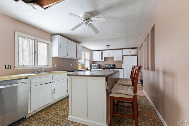 kitchen featuring sink, stainless steel appliances, a kitchen island, a breakfast bar area, and white cabinets