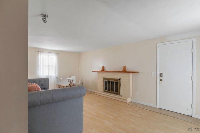 living room featuring a brick fireplace and light hardwood / wood-style flooring