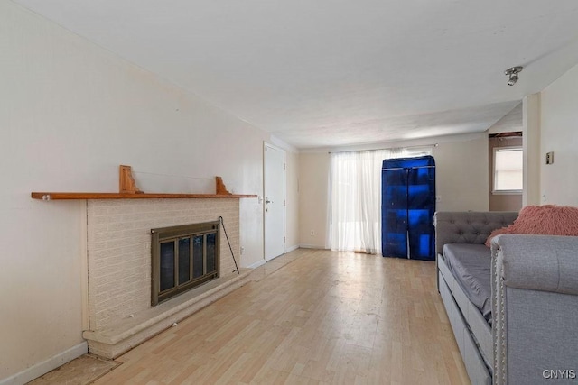 unfurnished living room featuring light hardwood / wood-style flooring and a brick fireplace