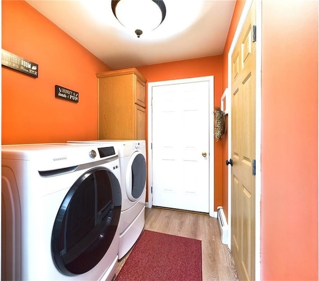 laundry area with cabinets, baseboard heating, washer and clothes dryer, and light hardwood / wood-style flooring