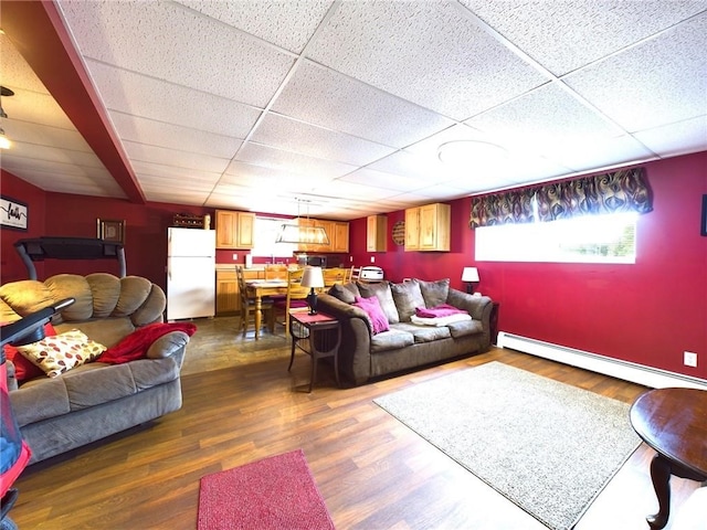 living room featuring a drop ceiling, hardwood / wood-style flooring, and a baseboard radiator