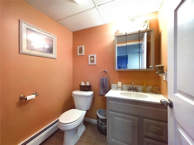 bathroom featuring toilet, hardwood / wood-style floors, a baseboard heating unit, a paneled ceiling, and vanity