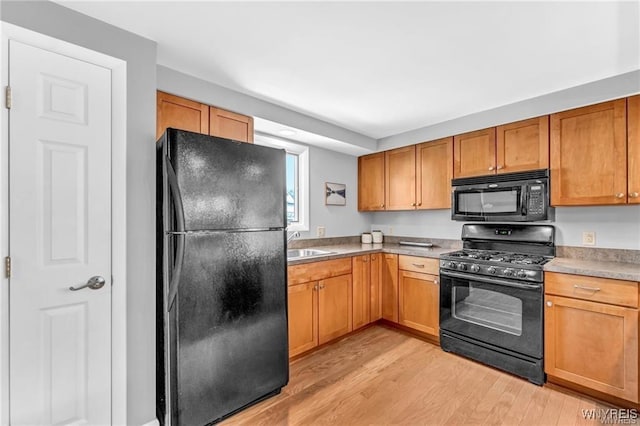 kitchen with light wood-style floors, light countertops, a sink, and black appliances