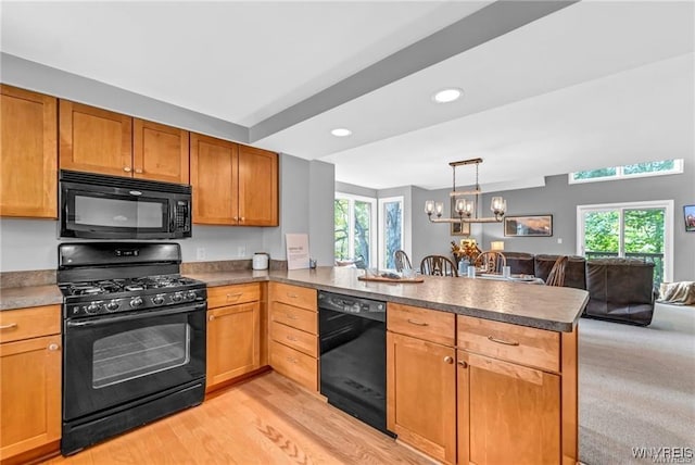 kitchen featuring a chandelier, light wood-style flooring, a peninsula, open floor plan, and black appliances