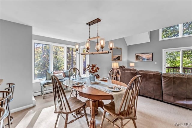 dining space featuring vaulted ceiling, a healthy amount of sunlight, a notable chandelier, and light carpet