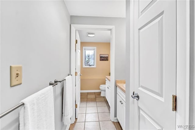 bathroom with toilet, tile patterned floors, baseboards, and vanity