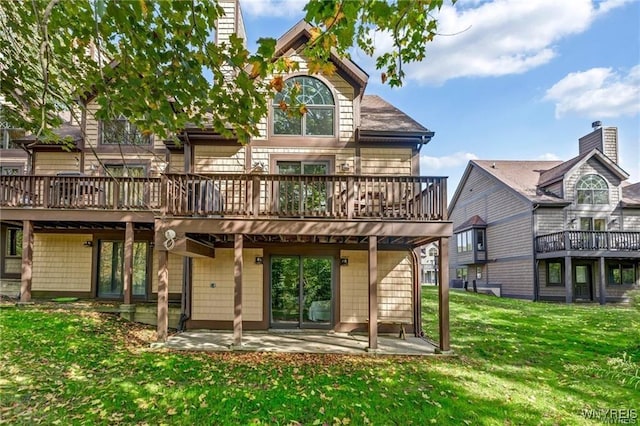 back of house with a yard, a wooden deck, and a patio