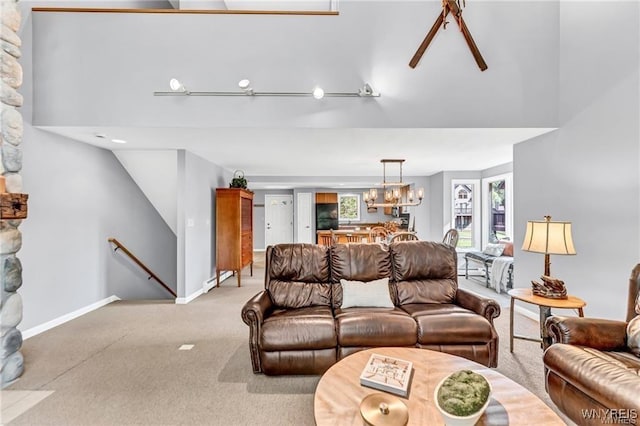 living area with light carpet, baseboards, a towering ceiling, and a chandelier