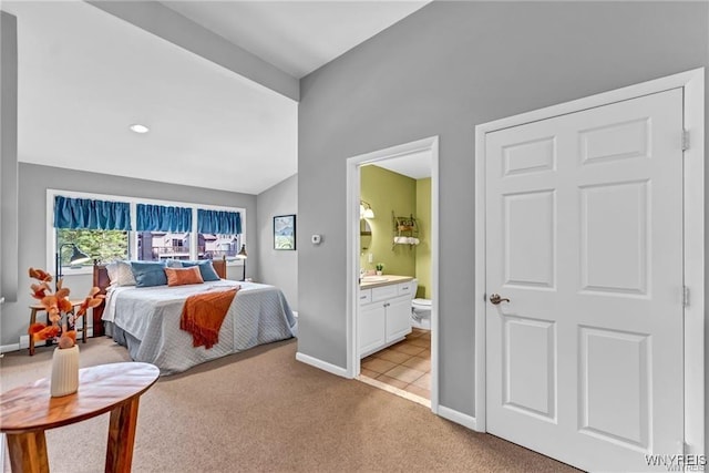 bedroom featuring lofted ceiling, baseboards, connected bathroom, and light colored carpet