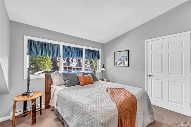 carpeted bedroom with a baseboard heating unit, multiple windows, vaulted ceiling, and baseboards