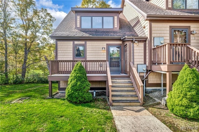 view of front of house featuring a deck, a shingled roof, stairway, and a front yard