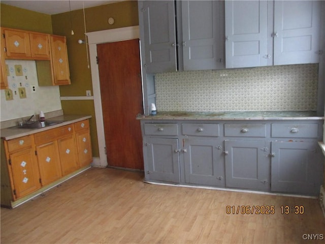 kitchen with decorative backsplash, light hardwood / wood-style floors, and sink