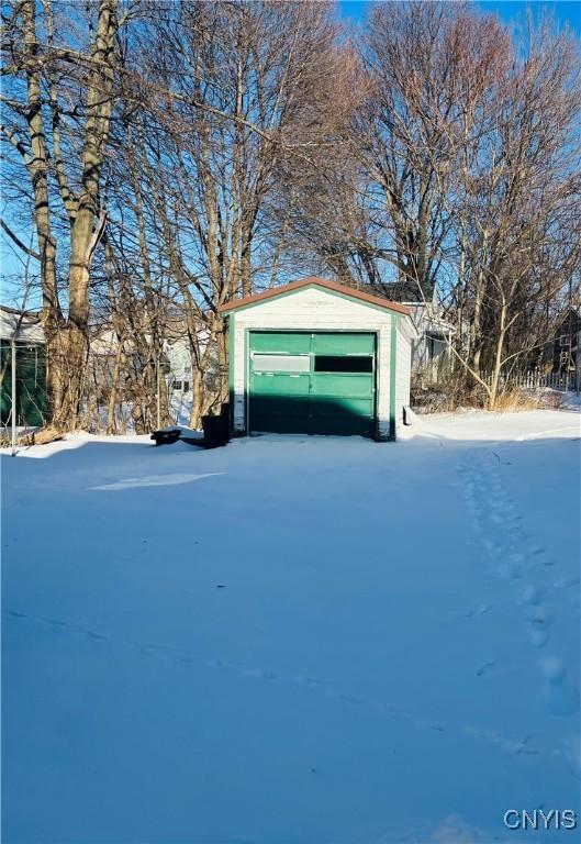 yard layered in snow featuring an outdoor structure and a garage