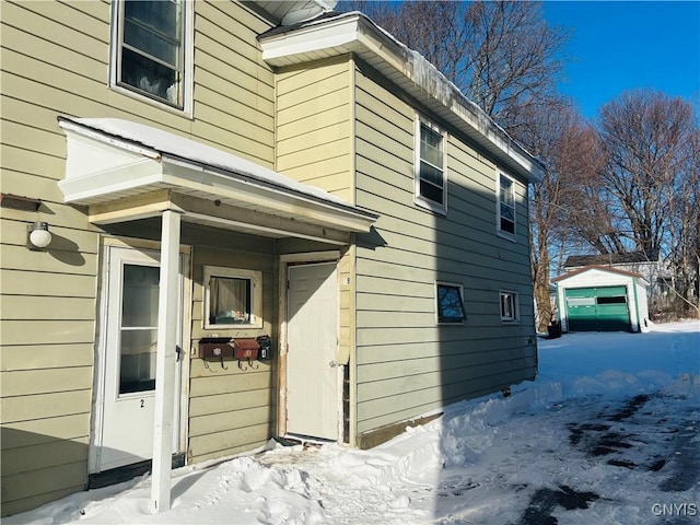 snow covered property with a garage and an outdoor structure