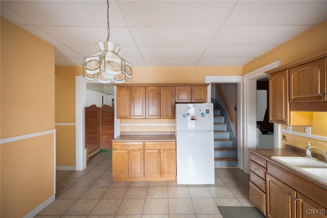 kitchen featuring sink, hanging light fixtures, a baseboard heating unit, white fridge, and a paneled ceiling